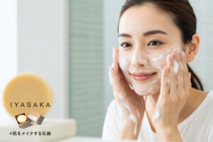 笑顔の女性が泡で洗顔しているシーン。手前に#肌をメイクする石鹸が映っている