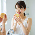 朝の日差しの中で笑顔の女性が泡立てた丸い洗顔石鹸を持つ写真