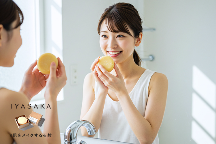 朝の日差しの中で笑顔の女性が泡立てた丸い洗顔石鹸を持つ写真