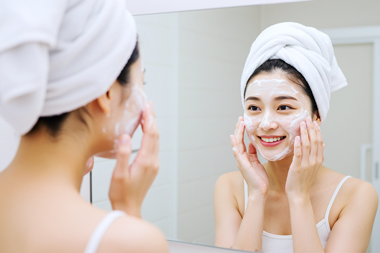 女性が泡で洗顔中に鏡で自分の肌を確認しているシーン。笑顔で鏡を見ている。