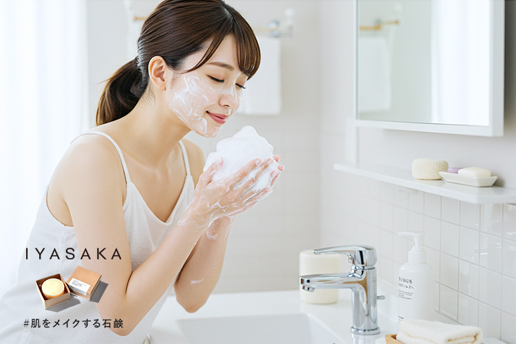 たっぷりの泡で洗顔する日本人女性。明るいバスルームの洗面台前でのシーン。