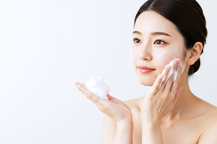 日本人女性が手のひらにきめ細かい泡をのせ、顔の中心から外側に向かって優しくマッサージしている洗顔シーン