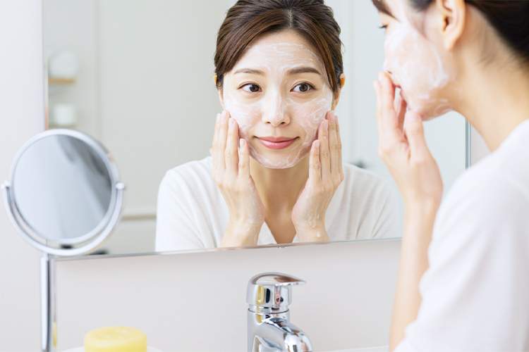 洗顔中のもちもち泡を鏡で確認する40代女性。