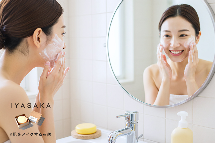 笑顔の女性が泡で洗顔するシーン。背景に#肌をメイクする石鹸が置かれたバスルーム